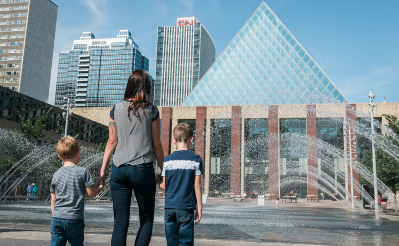 A woman and two kids standing in front of City Hall fountain.