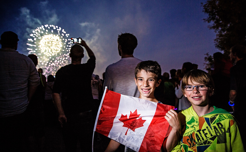 Kids holding a Canada flag during a fireworks display.
