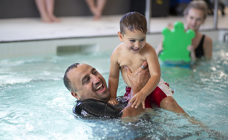A man and a child playing in a pool.