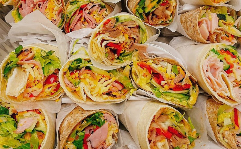 Various flavours of wrap-style sandwiches piled on top of each other.