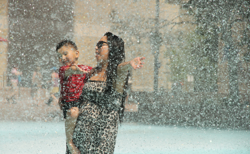 A woman holding a child in City Hall fountain.