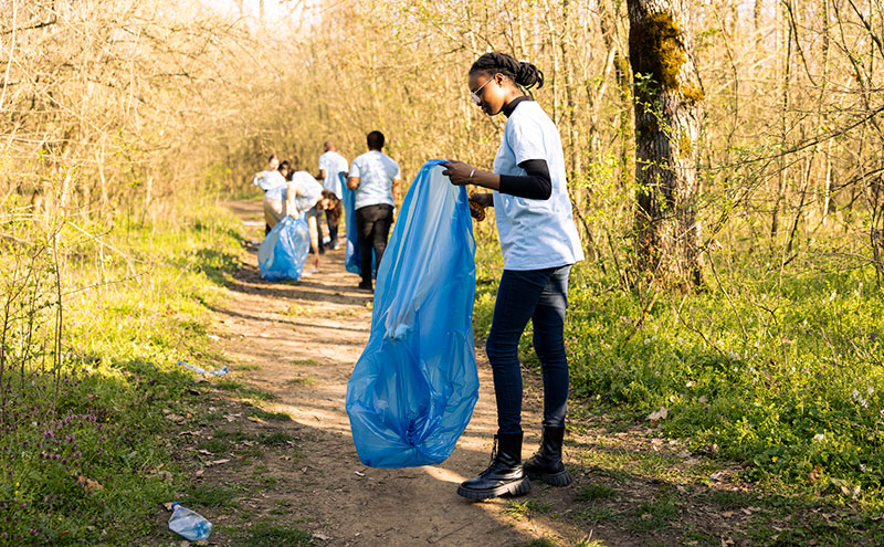 person picking up litter on trail