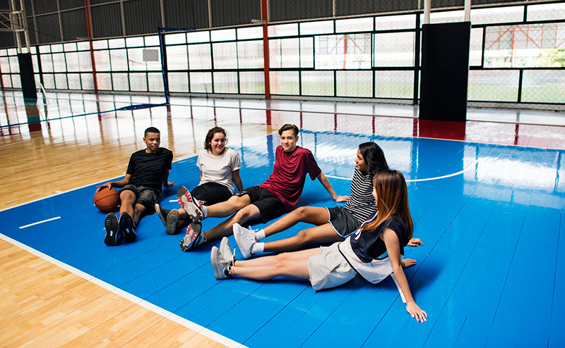 group of teens sitting on gym court ground
