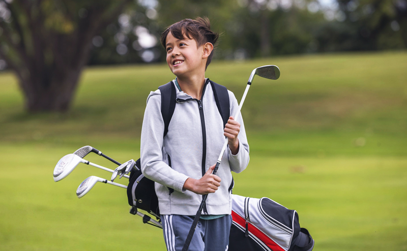 A child carrying golf clubs.
