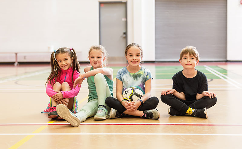 four kids sitting on gym floor