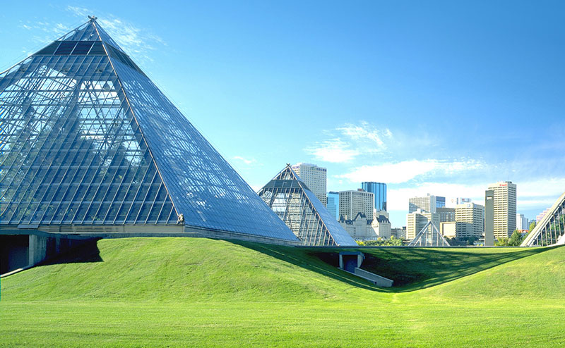 pyramids amongst green grass and city buildings backdrop