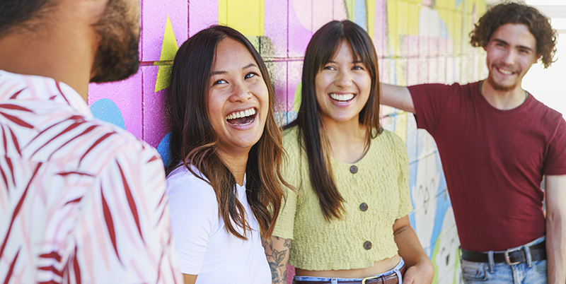Four youth standing in front a mural
