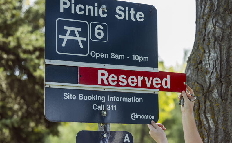 A picnic site sign being updated to "reserved"
