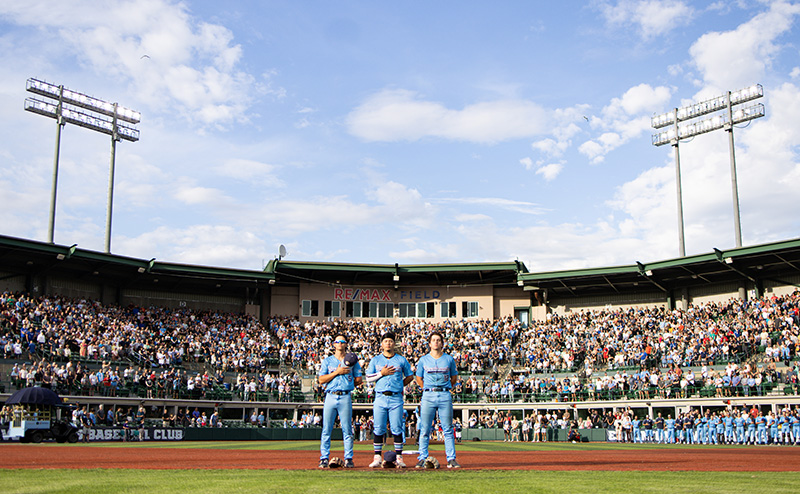 Riverhawks players standing in front of home plate with their back to fans