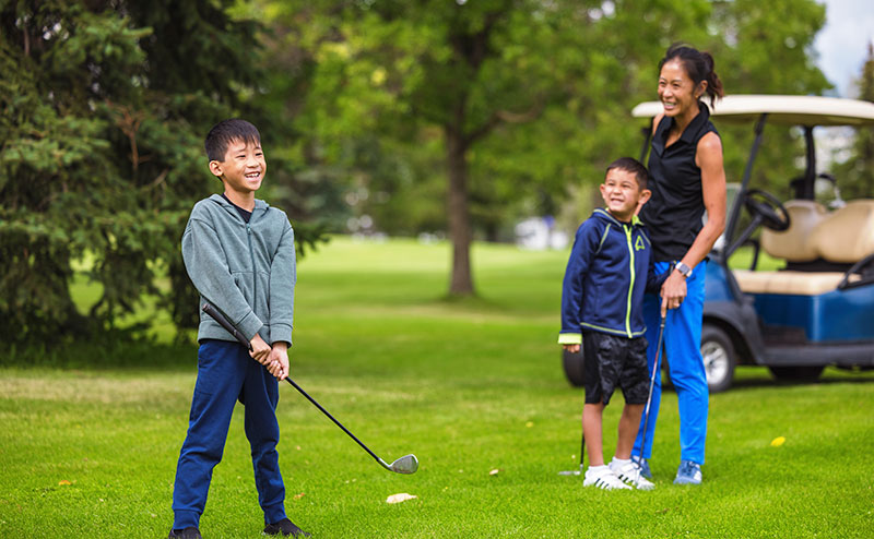 Family on golf green playing golf.