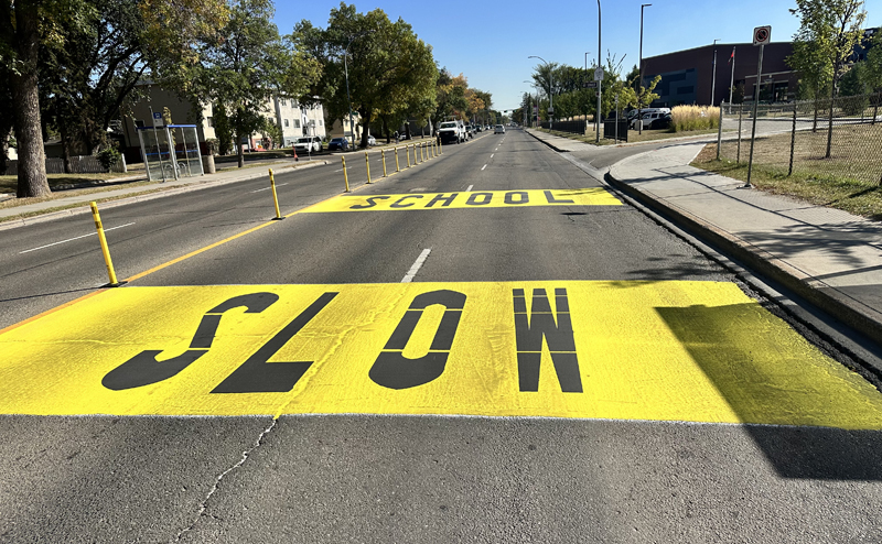 Playground zone speed limit sign with children crossing road in background