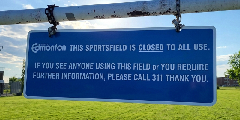 Blue sports fields closure sign with the text: This sports field is closed to all use. If you see anyone using this field or you require further information, please call 311. Thank you.
