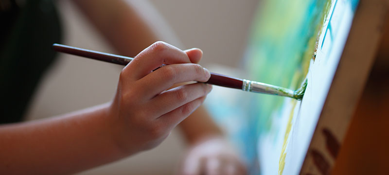 close up of hands painting a picture