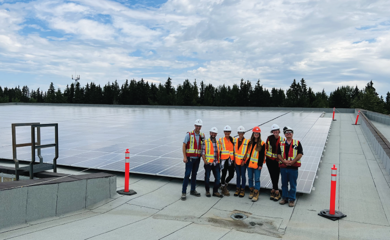 several Chandos employees wearing hardhats and safety vests standing next to a solar installation on a flat rooftop