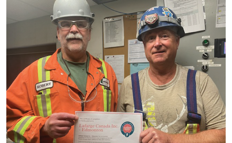 two Lafarge employees wearing hardhats holding up a certificate