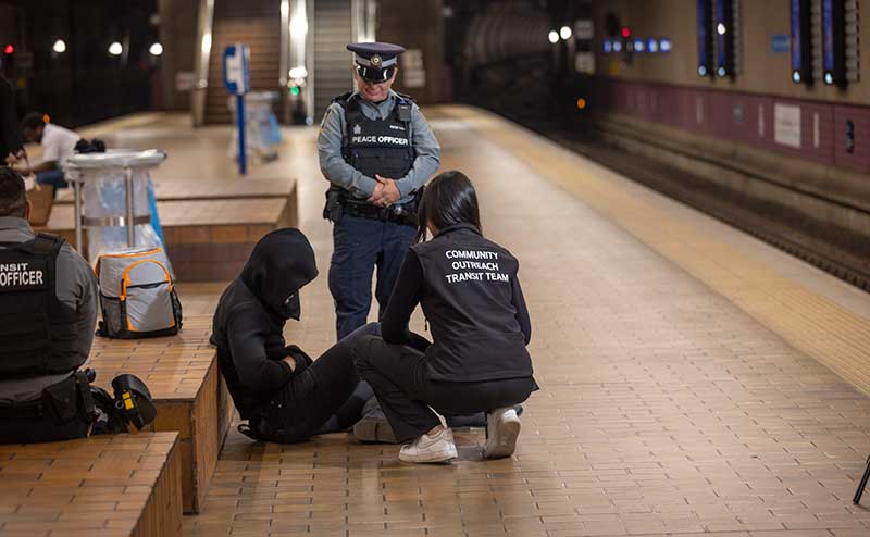 two enforcement officers helping someone in need at transit centre