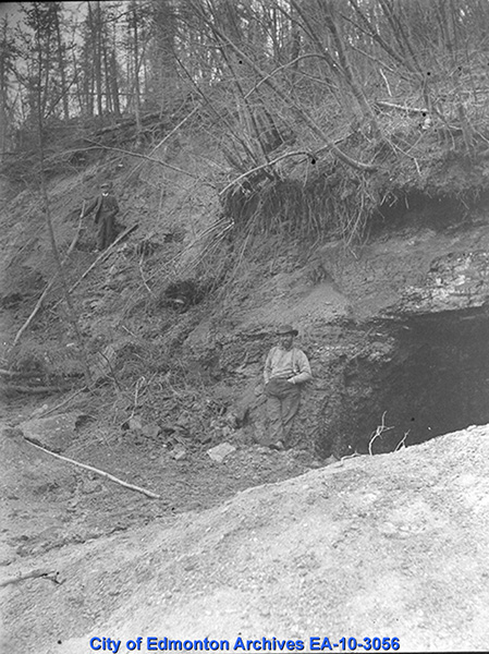 The opening of a coal mine, with a man standing at the entrance