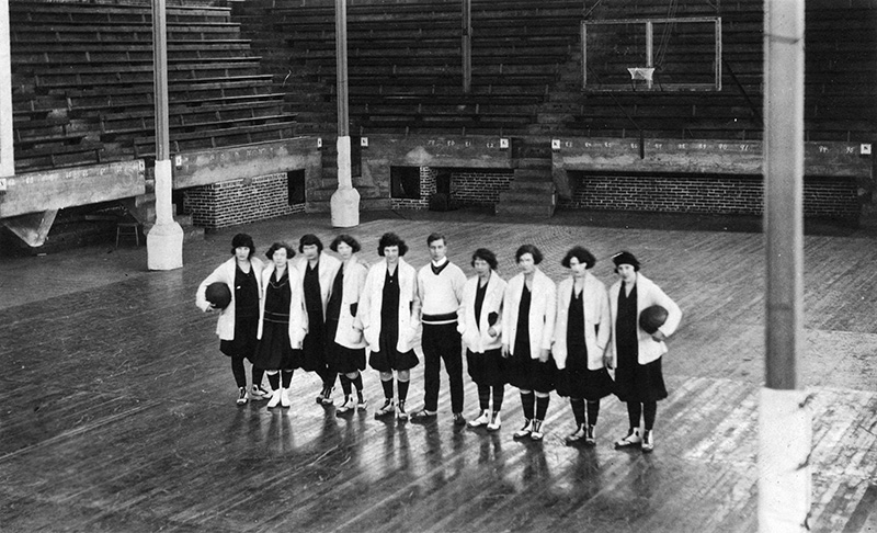 Black and white overhead photo of the Grads and Percy Page in a gymnasium.