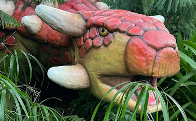 Sculpture of a dinosaur placed to look like it's eating real plants