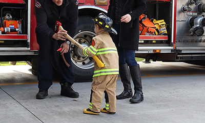 Safe exchange of axe between firefigher and young boy at a Station 17 open house.