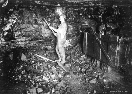 A miner using a pickaxe in a coal mine.