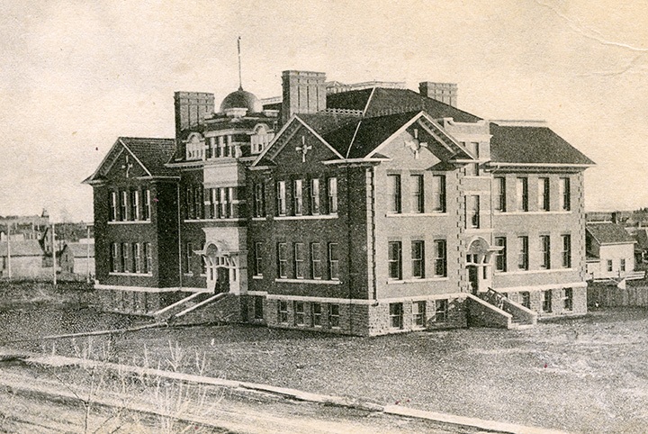 A black and white photo of a large 3 storey school.