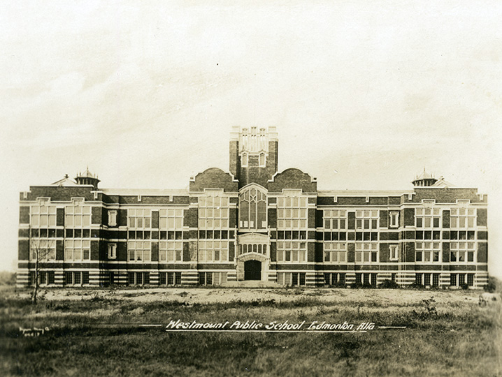 Sepia tone photo. A large multi-story school building. A single entrance exists in the middle of the building, with stairs leading up to it. Text overlaid at the bottom of the photo reads "Westmount Public School, Edmonton Alta.".