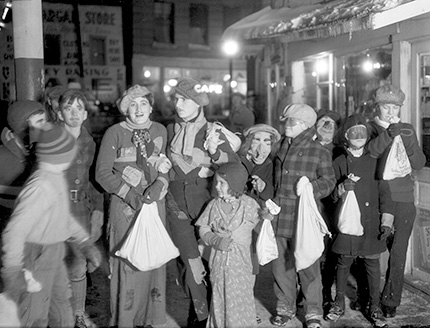 A group of children, all dressed in various costumes while holding bags of candy.