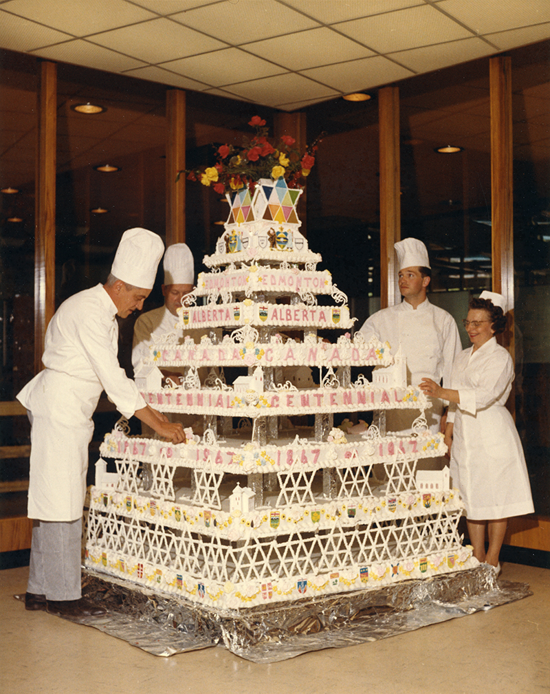 A large tiered cake being set up by chefs.