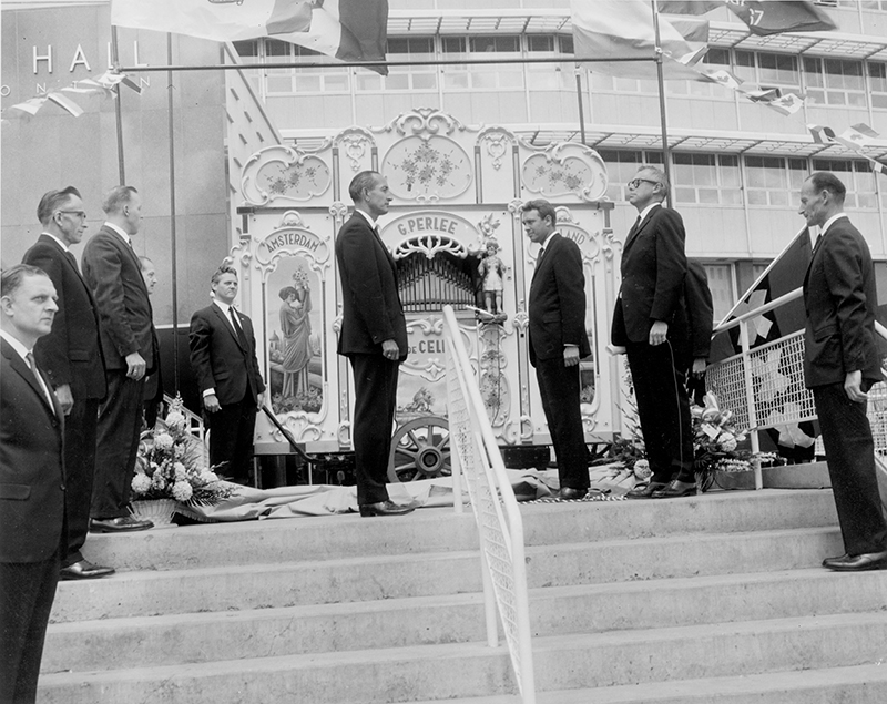 Black and white photo. Several men standing on the steps of Edmonton's City Hall. The Dutch Organ is in the background.