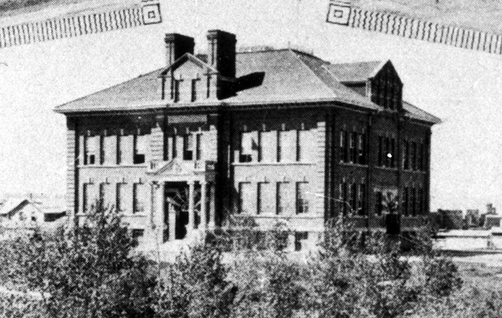 A black and white photo of a large brick school.