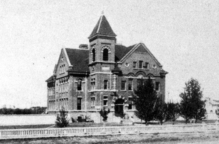 A black and white photo of an ornate brick school.