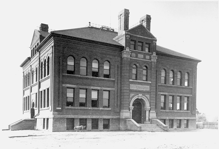 A black and white photo of a three storey brick building.