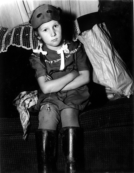 A young girl sitting cross-armed in a Halloween costume.