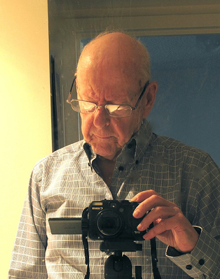 Chris Bruun interacting with a black camera on a tripod.