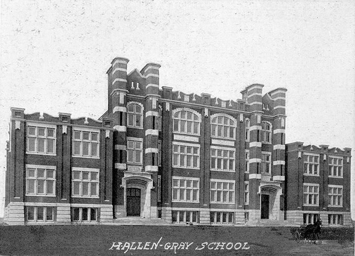 A brick school that spans across the image, and several windows.