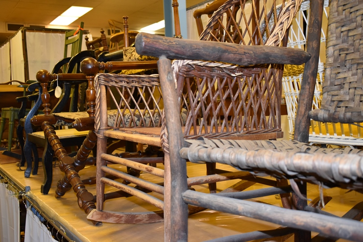 Close-up view of several old wooden chairs on display.