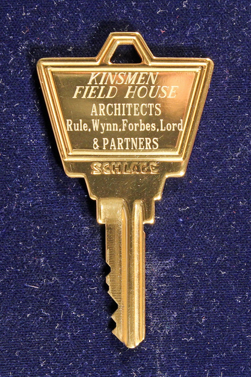 A gold key with engraving that reads "Kinsmen Field House".