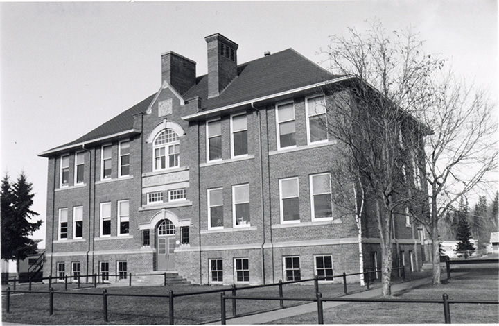 Black and white photo. A multi-story building. Each wall has several large windows.