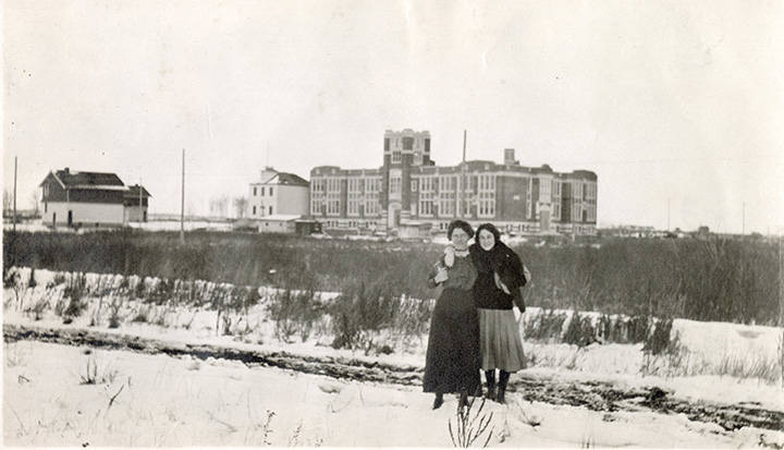 Two women standing before Highlands School in the distance.