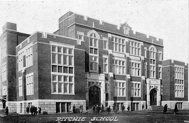 Black and white photo. A large multi-story school building. People, presumably students, are casually gathered outside. Text overlaid along the bottom of the photo reads "Ritchie School".