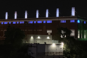 A photo of the outside of the Rossdale Power Plant lit up at night.