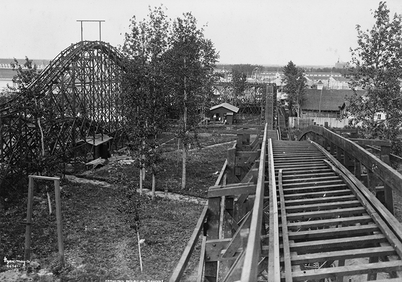 A black and white photograph of an old rollercoaster with wooden tracks.