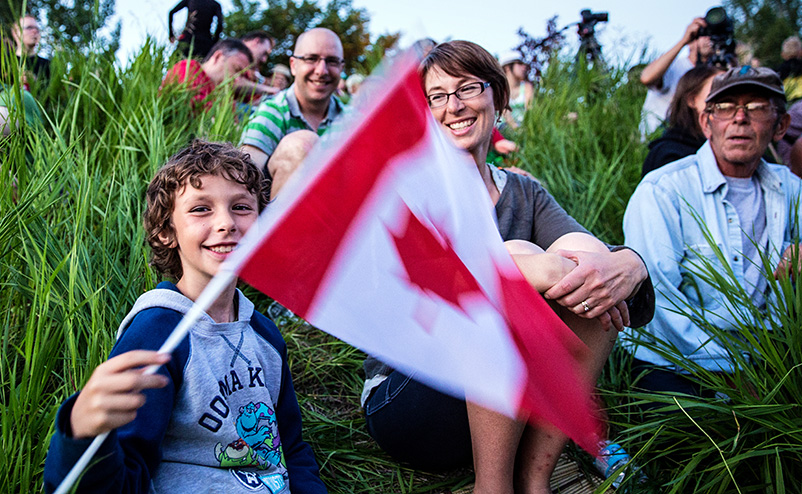 Persons sitting in grass during Canada day celebration