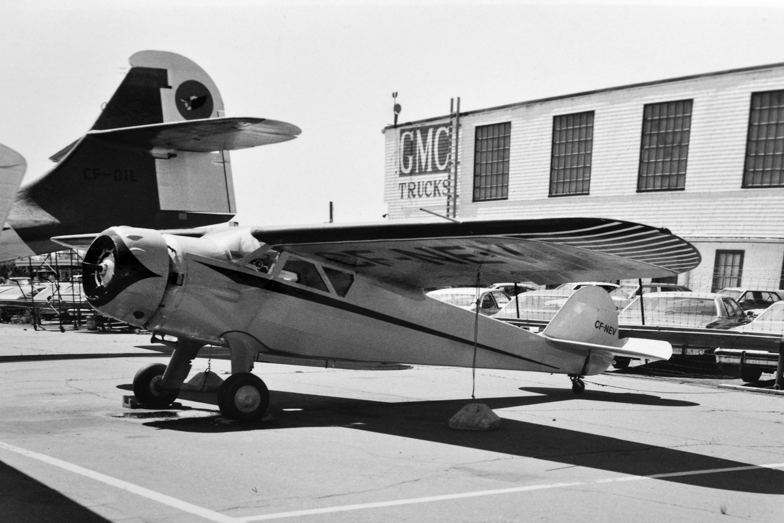Aircraft parked by GMC trucks by Hangar 14