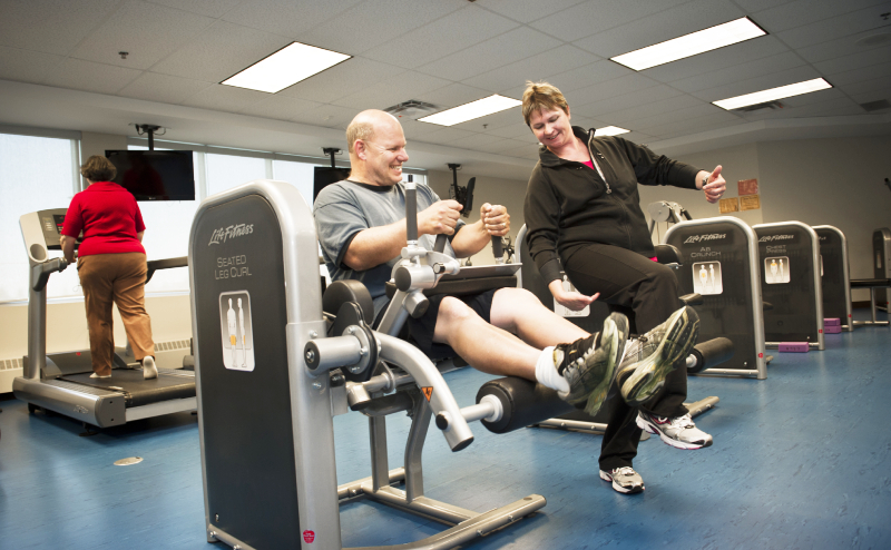 A man using exercise equipment being coached by a trainer at Central Lions.