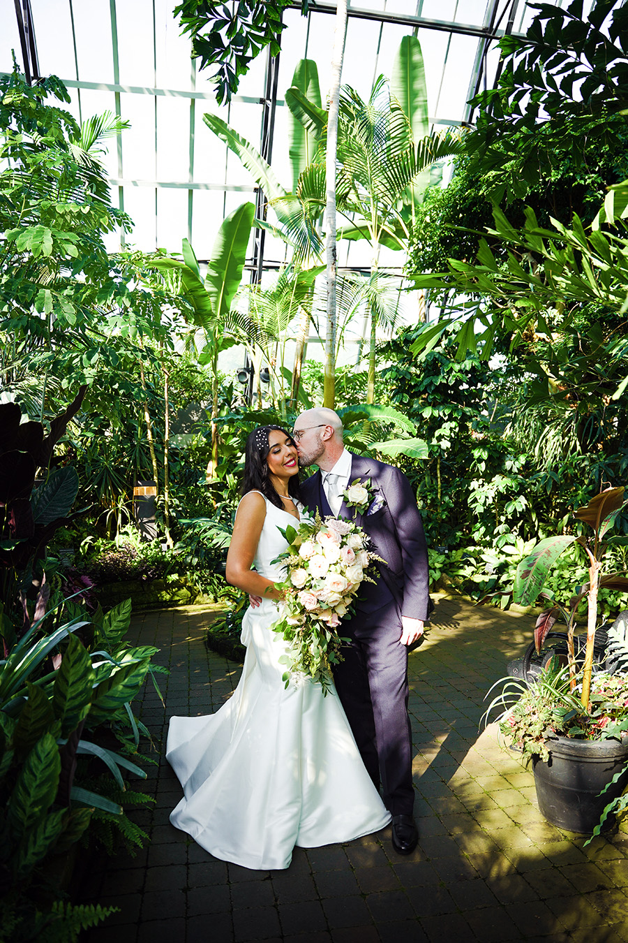 Wedding photo of bride and groom inside a pyramid surrounded by plants