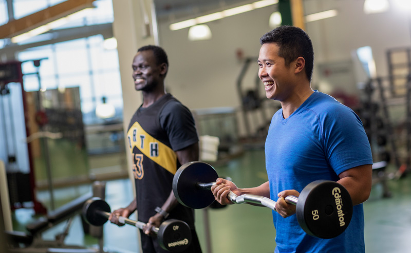 Two men working out in a fitness centre at a City Recreation Centre.