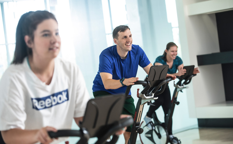 A man and two women working out on exercise bikes in a fitness centre at a City Recreation Centre.