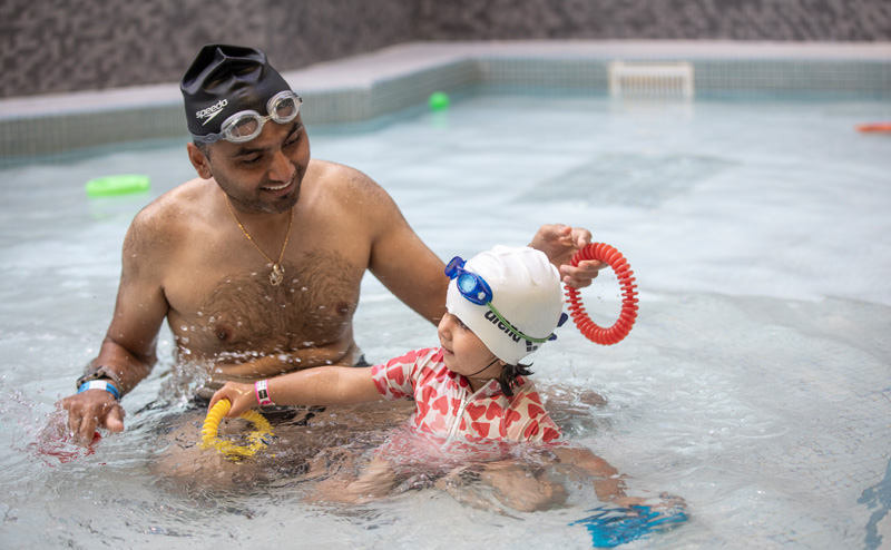 A man and a child playing in a City pool.
